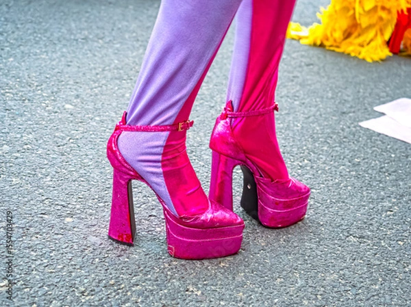Fototapeta A close-up of a woman's legs in pink high platform sandals designed for the show. The bright, thick tights with contrasting stripes create a striking stage look