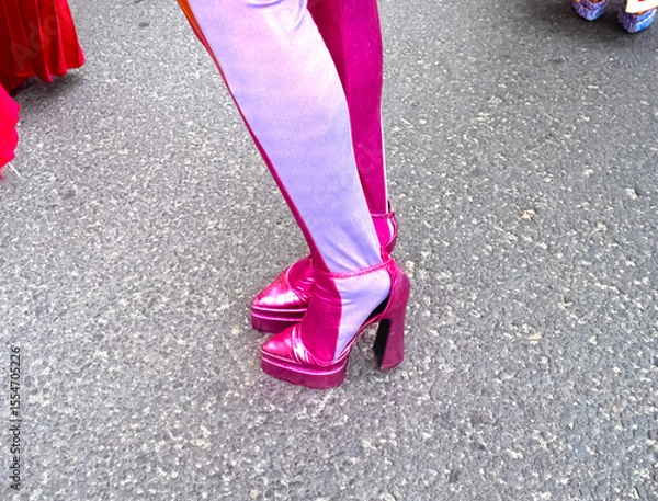 Fototapeta A close-up of a woman's legs in pink high platform sandals designed for the show. The bright, thick tights with contrasting stripes create a striking stage look