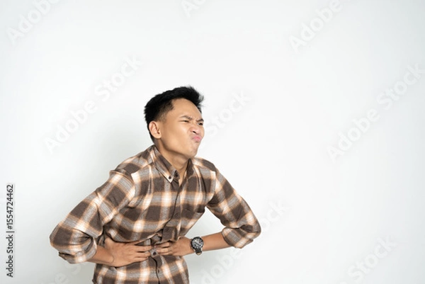 Fototapeta Person expressing abdominal pain while holding stomach. Depicts health issues and discomfort in individuals.