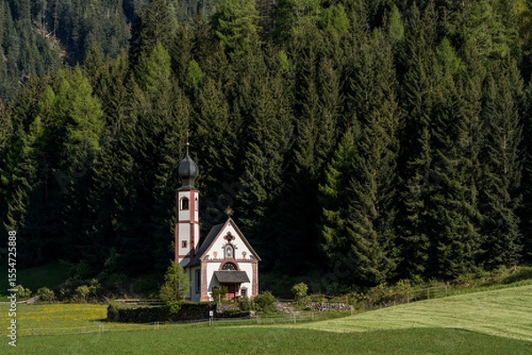 Fototapeta Church of St. John in Ranui in Val di Funes, Italy, with alpine meadow and Geisler Peaks in the background.