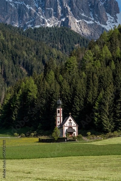 Fototapeta Church of St. John in Ranui in Val di Funes, Italy, with alpine meadow and Geisler Peaks in the background.