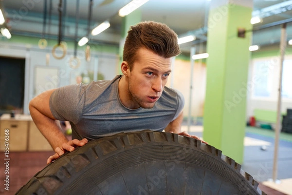 Fototapeta man doing strongman tire flip training in gym