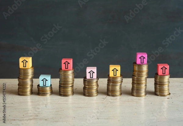 Obraz Business concept for financial growth, wealth mangement, making money or interest rate increase, inflation, high price, tax and tariffs rise . Arrow up sign on wooden cube blocks above stack of coins,