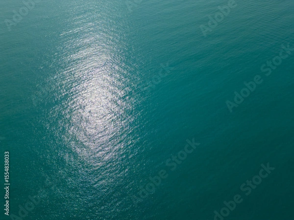Fototapeta Aerial view of calm turquoise sea with shimmering sunlight reflections on the surface. Peaceful and abstract natural background