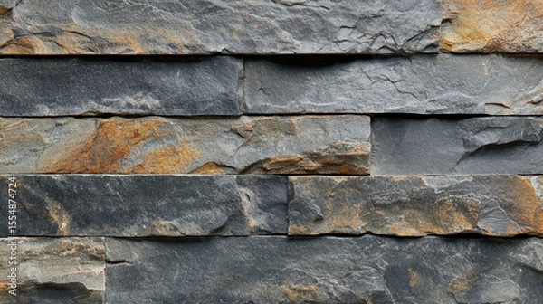 Fototapeta Close-up of a textured dark gray stone wall with layered natural slate stones stacked horizontally