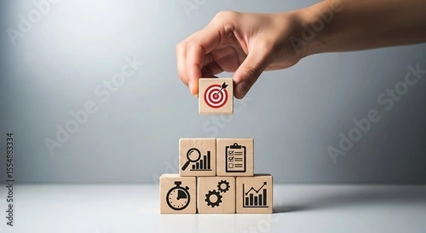 Obraz Hand Placing Wooden Block with Target Icon on Top of Stack of Blocks Showing Business Icons Stopwatch Graph