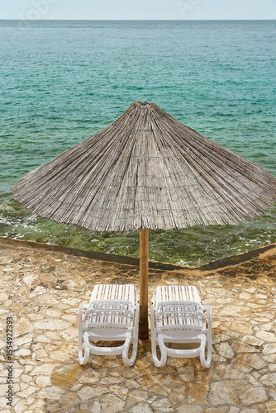 Obraz Sonnenschirm und Sonnenliegen an einer typischen Bdestelle am Strand von Porec an der kroatischen Küste der Adria