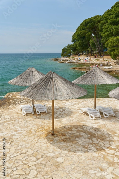Obraz Sonnenschirme und Sonnenliegen an einer typischen Bdestelle am Strand von Porec an der kroatischen Küste der Adria
