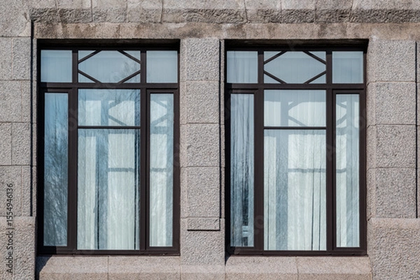 Fototapeta Two rectangular windows with brown frames against a wall of grey blocks. From the Windows of the World series.
