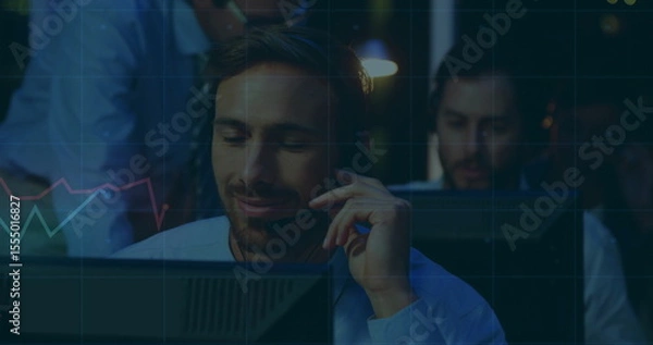 Fototapeta Analyzing trader in blue shirt tracking market data in trading office with headset monitors, charts