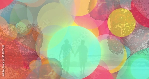 Obraz Walking senior couple holding hands on shallow sandy shore, with translucent circles over sea waves