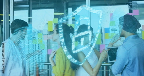Obraz Collaborating team analyzing sticky notes on glass wall in office, with tablet and shield icon