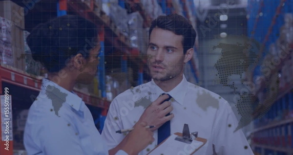 Fototapeta In warehouse, workers discussing logistics with animated world map overlay