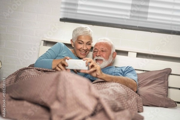 Obraz Senior couple lying in bed together using a digital tablet