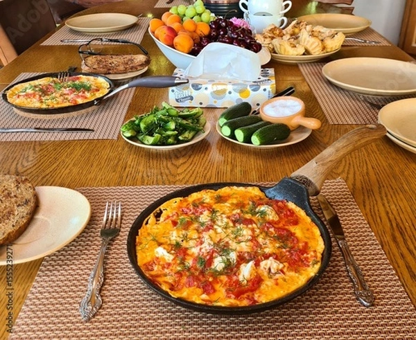 Fototapeta Frying pan with fried eggs and tomatoes prepared for breakfast in village