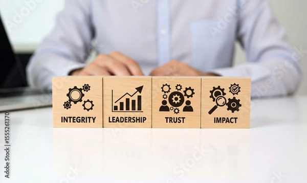 Fototapeta Four wooden blocks representing key business concepts integrity with gears leadership with a growth chart trust with people and gears and impact with a magnifying glass and gears