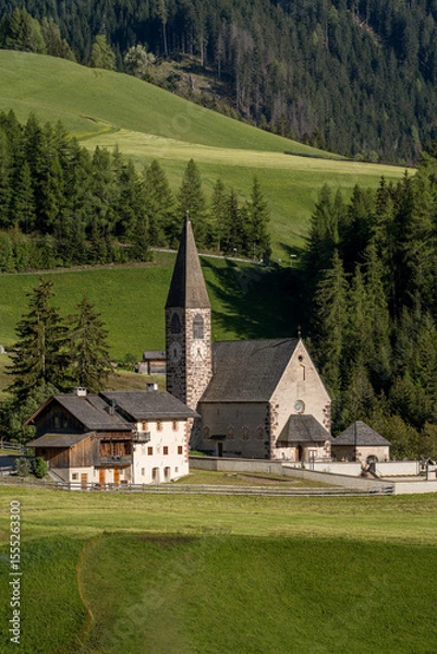 Fototapeta Close-up view of Santa Maddalena Church in the green valley of South Tyrol with forested hills in the background.