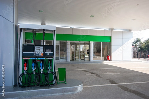 Fototapeta Modern, clean gas station with multiple fuel pumps and convenience store entrance, ideal for themes of travel, transportation, and energy infrastructure