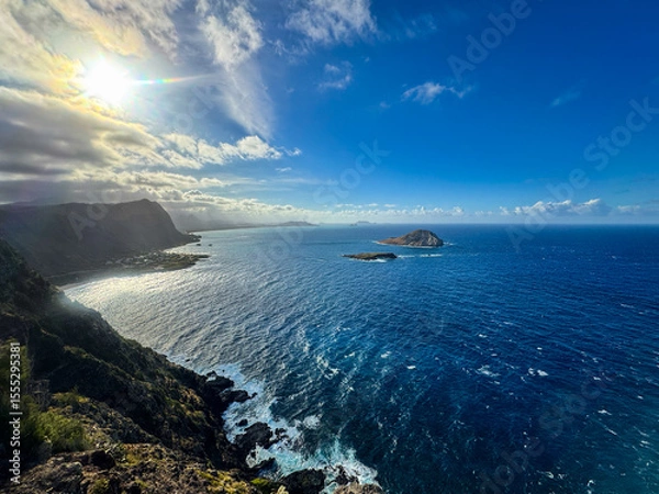 Fototapeta Stunning aerial view of Rabbit Island from Makapuʻu Lighthouse, Oahu—turquoise Pacific waves crash along the dramatic volcanic coastline under a vibrant Hawaiian sky.