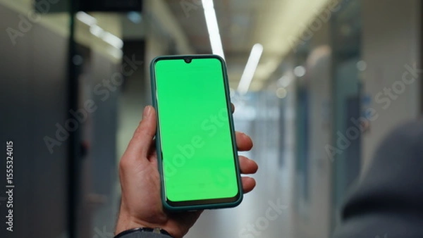 Obraz Hands holding mockup mobile phone in office vestibule closeup. Man strolling