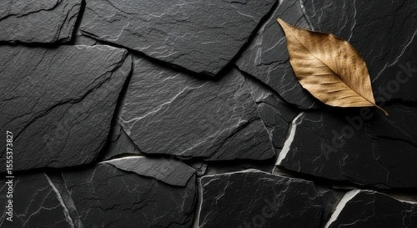 Obraz A fallen golden leaf resting on a dark stone tile arrangement pattern view