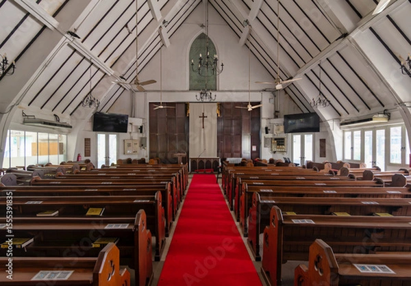 Fototapeta Bright red carpet leads to the altar in St. Marys Cathedral in Kuala Lumpur. High wooden beams and stained glass create a peaceful atmosphere for visitors