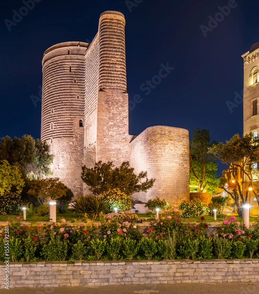 Fototapeta Maiden Tower, or Qiz Qalasi, illuminated at night in Baku, Azerbaijan, with a garden foreground