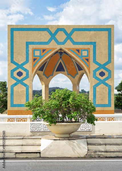 Fototapeta Ornate arch at the Seri Perdana Bridge in Putrajaya, Malaysia, with Islamic geometric mosaic tile patterns against a blue sky