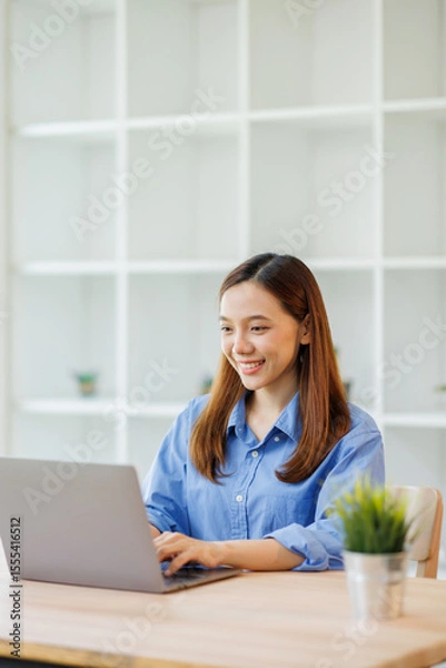 Obraz Young attractive business asian woman working on her project with laptop computer in modern workplace office room.
