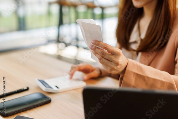 Obraz asian young woman hand checking list with bill for calculate accounting expense credit card payment on due deadline, trying to find money to pay debt on table. Business financial concept,
