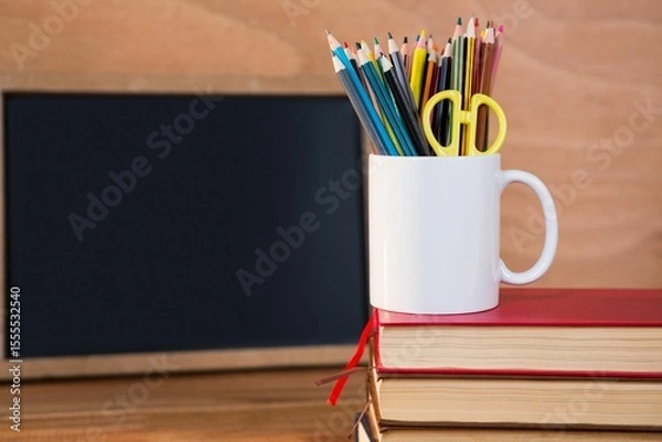 Fototapeta Desk organizer on stack of books against blackboard
