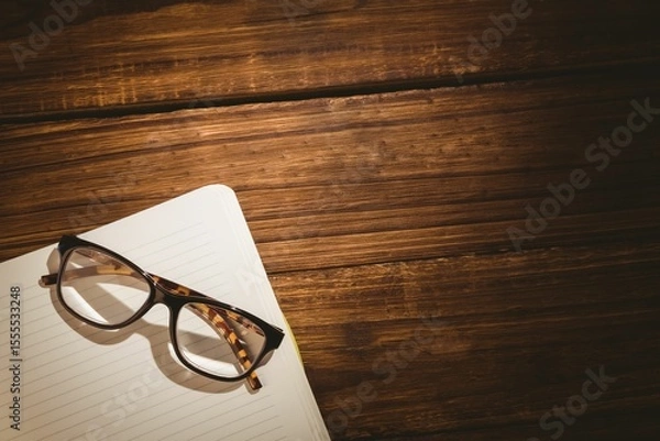 Obraz Reading glasses on book over wooden table