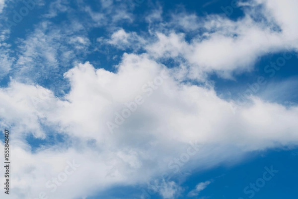 Fototapeta White fluffy clouds floating peacefully in the bright blue sky