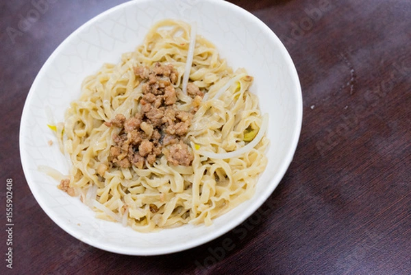 Obraz A bowl of Taiwanese-style dry noodles topped with savory minced pork sauce, scallions, and soy-based seasoning. A beloved comfort food offering rich umami and chewy texture.