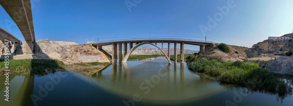 Fototapeta Nallihan Bird Sanctuary Ankara Turkiye  Panoramic View of a Modern Arch Bridge Spanning a River. A wide-angle, panoramic shot of a modern arch bridge gracefully spanning a calm river.