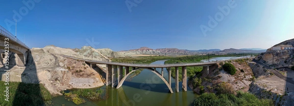 Fototapeta Nallihan Bird Sanctuary Ankara Turkey Panoramic view of a modern arch bridge spanning a river. This panoramic shot showcases a modern arch bridge gracefully crossing a river. Nallıhan Kus Cenneti
