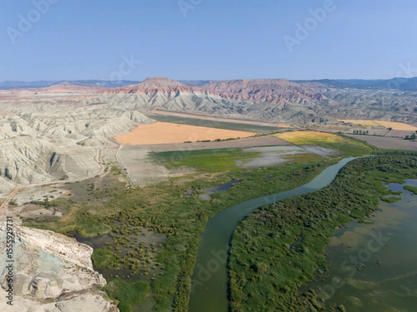 Fototapeta Nallıhan Kus Cenneti Nallihan Bird Sanctuary Aerial View of a Winding River through Colorful Desert Landscape. An expansive aerial shot showcasing a river snaking through a colorful desert landscape.