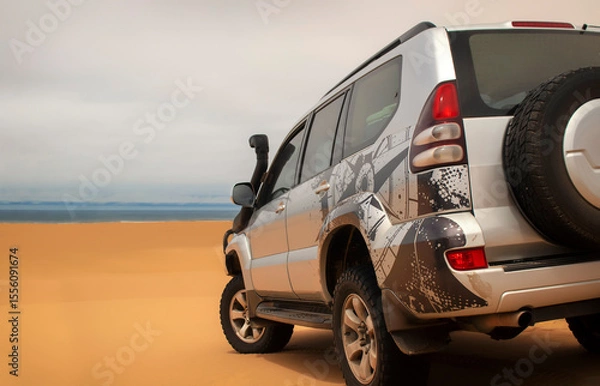 Fototapeta A powerful gray 4x4 SUV stands alone in the vast sandy terrain of the Namib Desert, ready for off-road travel, exploration, and endurance across one of Africa’s wildest landscapes. 