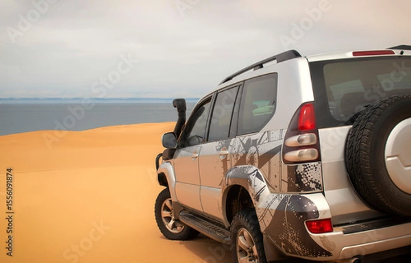 Fototapeta A powerful gray 4x4 SUV stands alone in the vast sandy terrain of the Namib Desert, ready for off-road travel, exploration, and endurance across one of Africa’s wildest landscapes. 