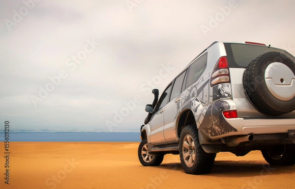 Fototapeta A powerful gray 4x4 SUV stands alone in the vast sandy terrain of the Namib Desert, ready for off-road travel, exploration, and endurance across one of Africa’s wildest landscapes. 