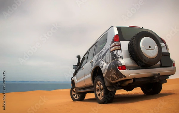 Fototapeta A powerful gray 4x4 SUV stands alone in the vast sandy terrain of the Namib Desert, ready for off-road travel, exploration, and endurance across one of Africa’s wildest landscapes. 