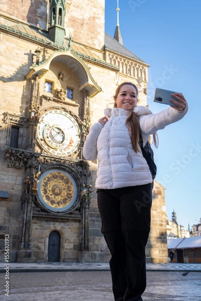 Obraz Mujer feliz paseando por el centro de Praga, tomandose una selfie con el reloj astronómico de fondo