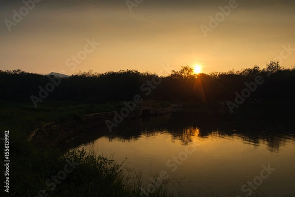 Obraz Serene Sunset Landscape Over a Peaceful Forest and Still River Reflection