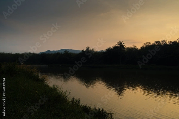 Obraz Tranquil Sunset Over a Serene Riverside With Reflections and Silhouetted Trees