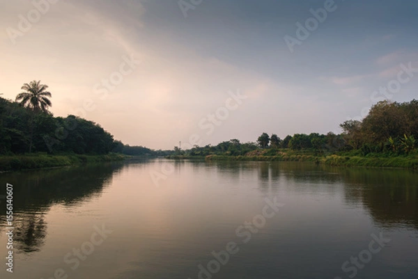 Obraz Calm River Flowing Through Lush Landscape with Trees and Gentle Reflections
