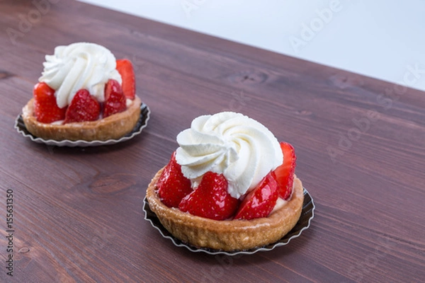 Obraz Two gorgeous strawberry tarts with chantilly cream - tartellete - on an ipe natural wood table - side view