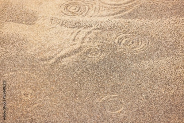 Fototapeta Raindrops creating circular ripples on rough asphalt during summer rain shower. 