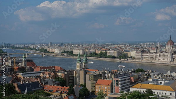 Fototapeta Wide-angle view of the Hungarian Parliament Building and Danube River with boats and surrounding architecture in Budapest.