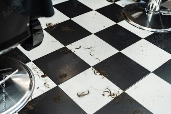 Obraz Hair clippings scattered on a black and white tiled floor in a salon
