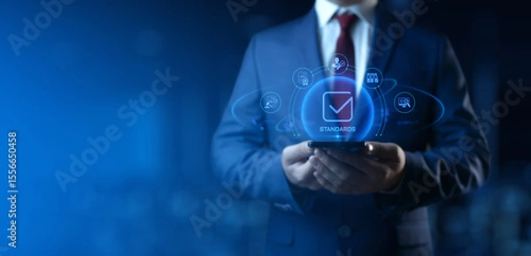 Fototapeta Businessman Holding smartphone with Standards Icons on Screen. Quality Management concept